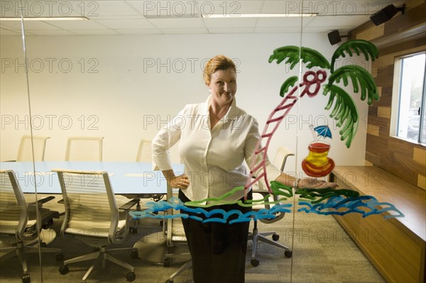 Caucasian businesswoman looking at drawing on conference room wall