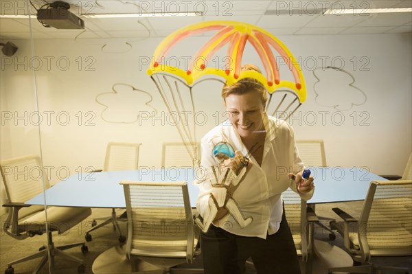 Caucasian businesswoman drawing a golden parachute on conference room wall