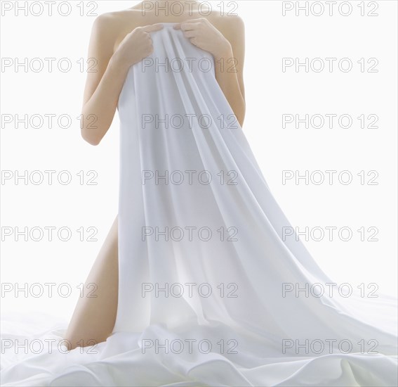 Nude woman covering herself with sheet