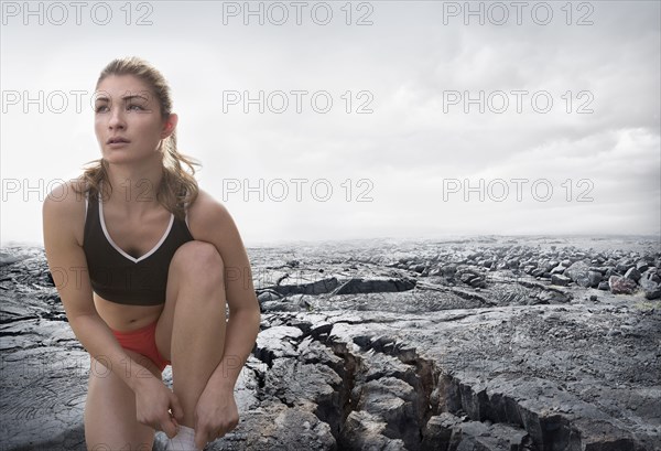 Caucasian runner tying shoes on rock formation