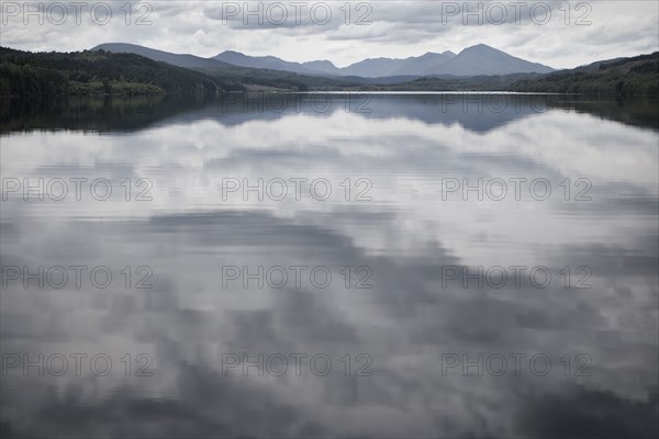 Cloudy sky reflected in still rural lake