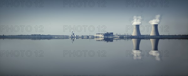 Smoke stacks and factory reflected in still lake