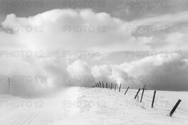Clouds and wooden fence in snowy landscape
