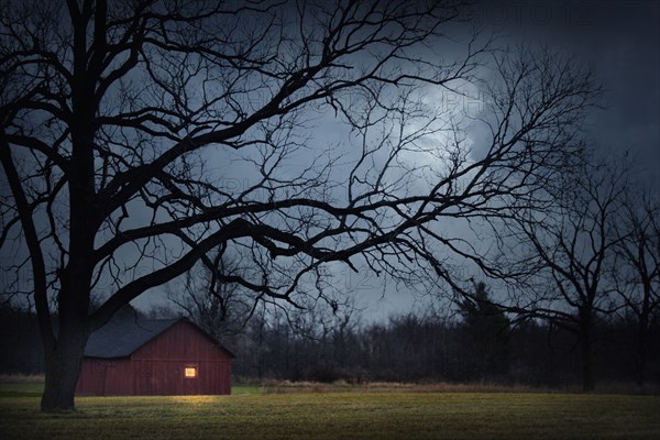 Illuminated barn in rural landscape