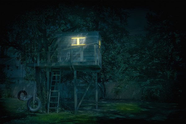 Illuminated treehouse in backyard at night