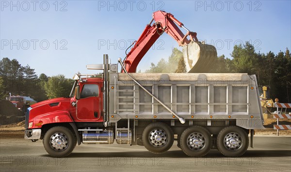 Digger scooping into dump truck on site