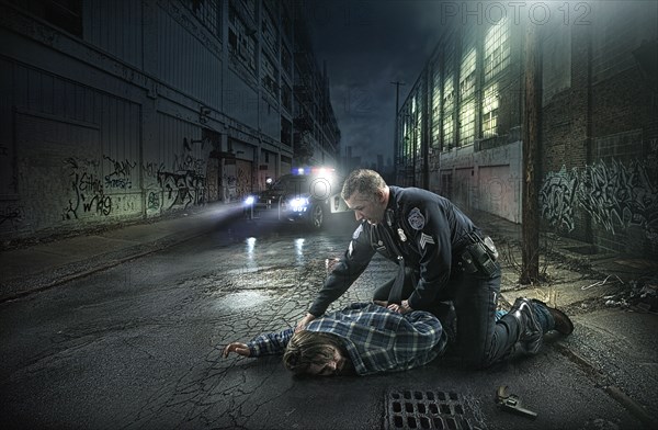Policeman arresting man on city street