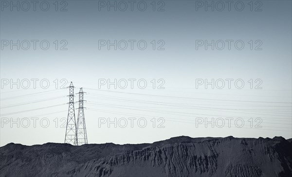 Silhouette of power lines over rocky landscape