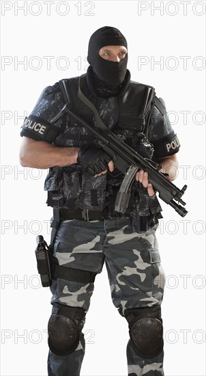 Police officer in gear holding assault rifle