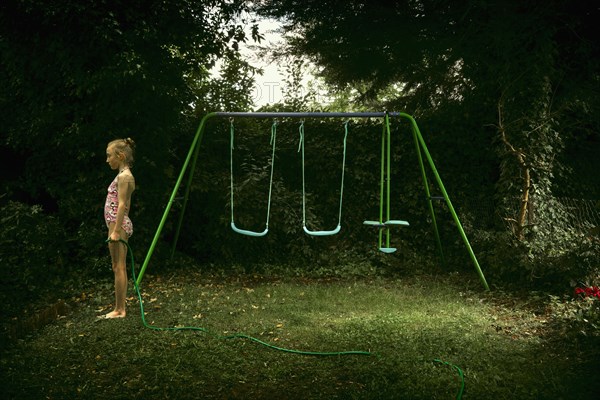 Caucasian girl standing near swing set in backyard