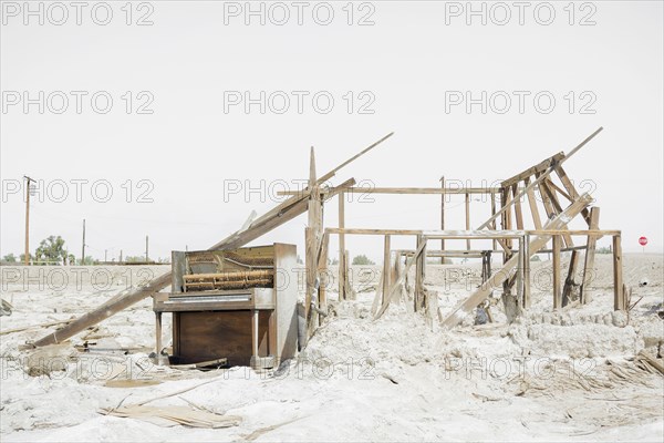 Dilapidated piano and abandoned structure in dirt lot