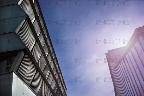 Low angle view of sunbeams over modern buildings