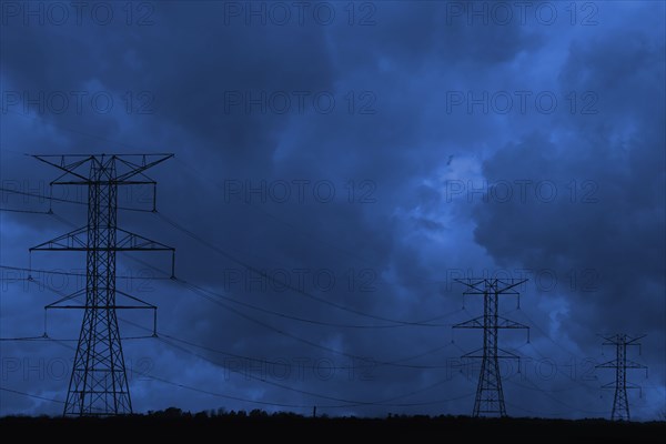 Silhouette of power lines under dark cloudy sky