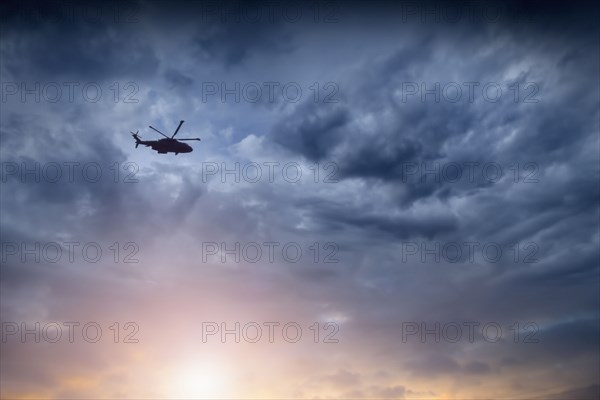 Low angle view of helicopter flying in cloudy sky