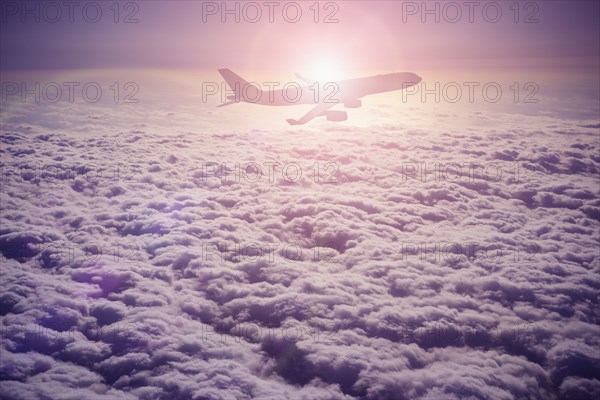 Silhouette of airplane flying over clouds