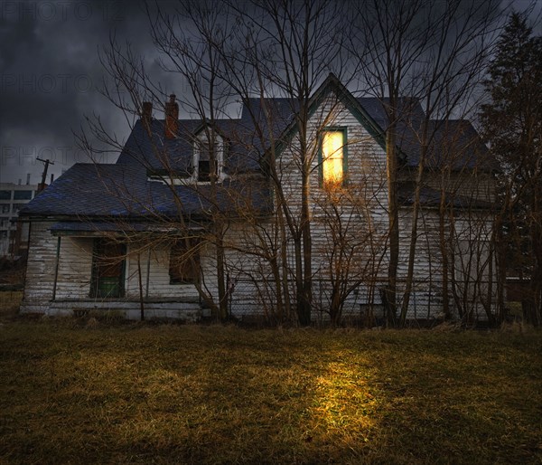 Glowing window casting light in backyard