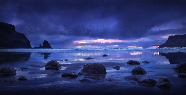 Rocks on beach under storm clouds