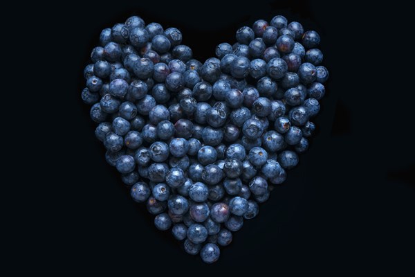 Blueberries in shape of heart on black background