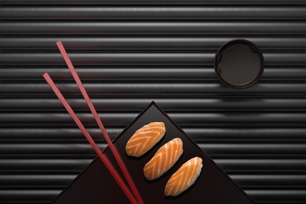 Chopsticks and sushi on square plate with dipping sauce