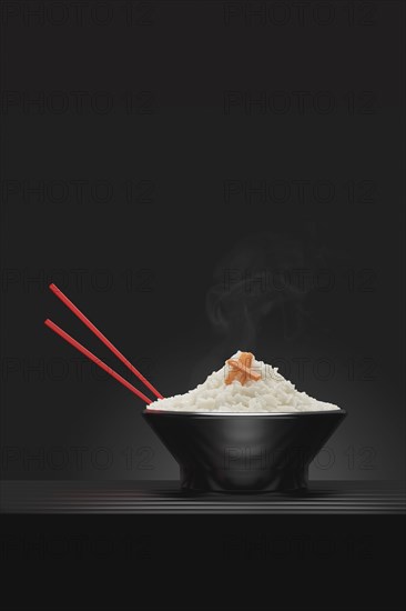 Chopsticks in bowl of steaming white rice