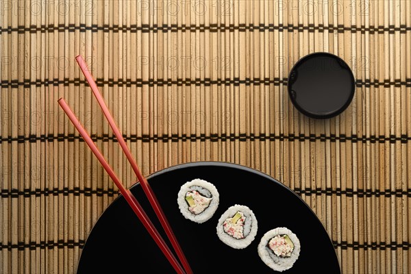 Chopsticks and sushi on round plate with dipping sauce