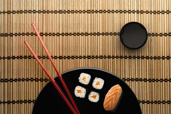 Chopsticks and sushi on round plate with dipping sauce