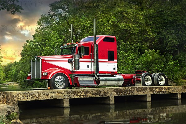 Semi-truck driving on bridge over river