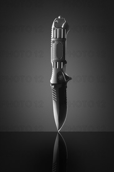 Switchblade balancing on gray background