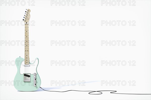 Green guitar balancing on white background