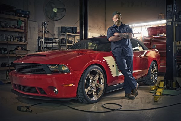 Caucasian mechanic posing on red sports car