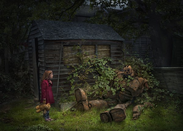 Caucasian girl with teddy bear discovering broken robot in garden