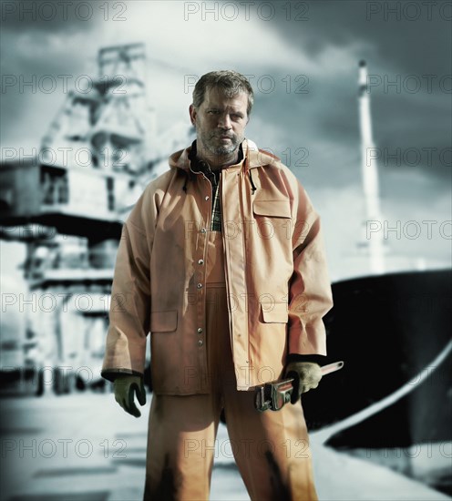 Serious Caucasian worker holding wrench on oil rig