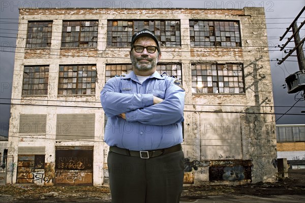 Caucasian security guard outside dilapidated building