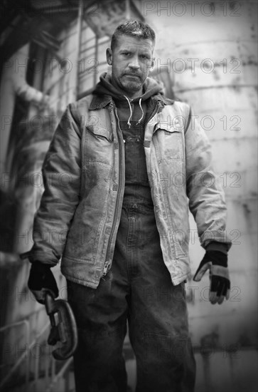 Serious Caucasian worker holding wrench on oil rig