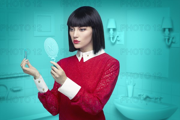 Caucasian woman in teal old-fashioned bathroom applying lipstick