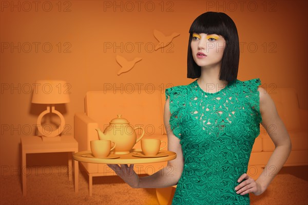 Caucasian woman in orange old-fashioned livingroom holding tea service