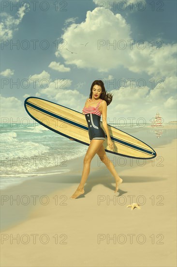 Caucasian woman running on beach carrying surfboard