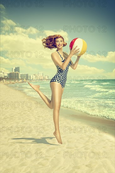 Caucasian woman running on beach carrying beach ball