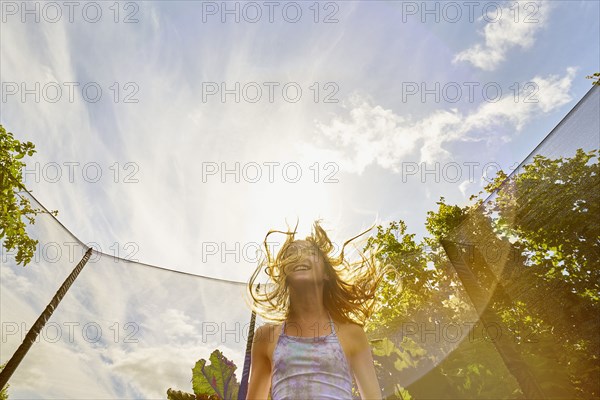 Low angle view of Caucasian girl jumping on trampoline