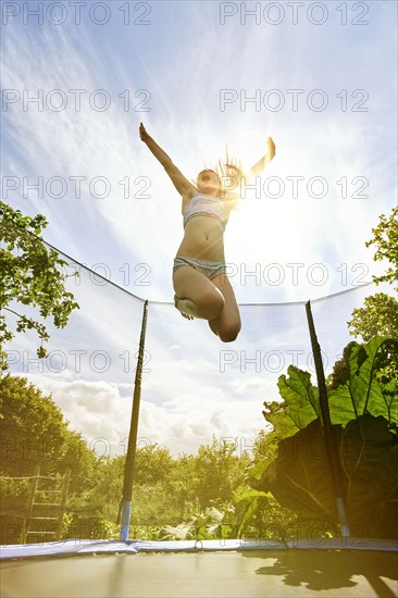 Low angle view of Caucasian girl jumping on trampoline