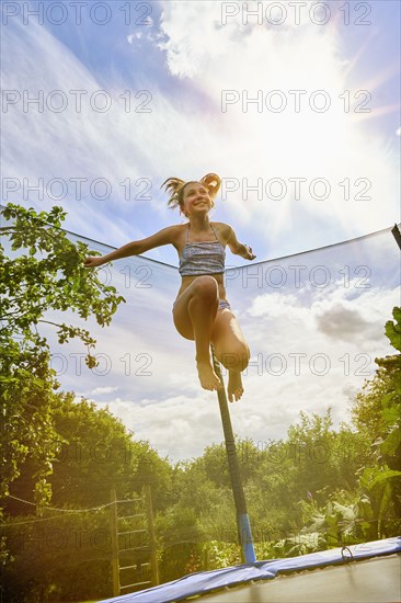 Low angle view of Caucasian girl jumping on trampoline