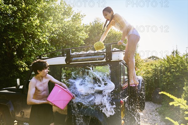 Caucasian boy splashing water from bucket on truck