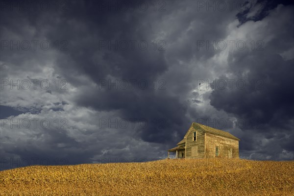 Storm clouds over remote wooden farmhouse