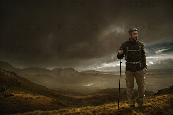 Caucasian hiker holding walking stick in cloudy landscape