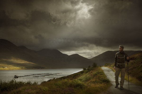 Caucasian hiker holding walking stick on path near river