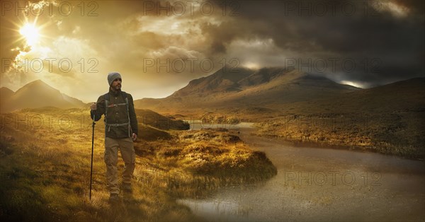 Caucasian hiker holding walking stick near mountain river at sunset