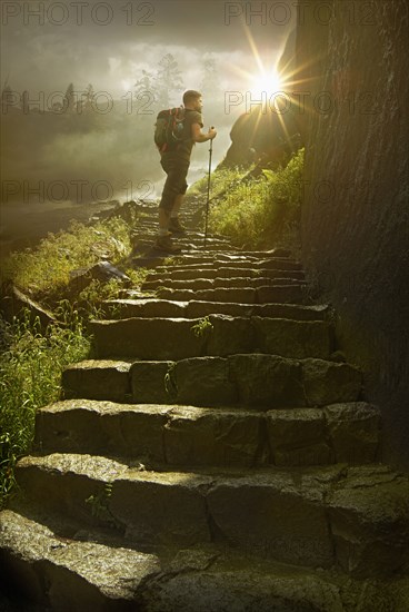 Caucasian hiker holding walking stick on sunny mountain path