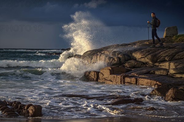 Distant Caucasian woman hiking on rocks near ocean