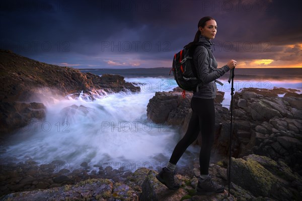 Caucasian woman hiking on rocks near ocean