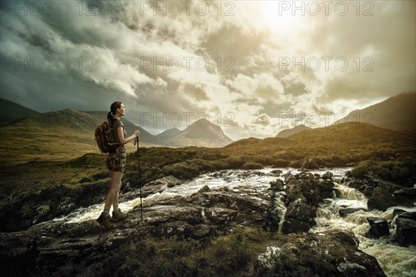 Caucasian woman hiking on rocks near river